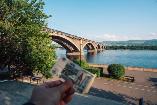 Night view of the famous Communal bridge in Krasnoyarsk through the Yenisei River in Russia, Krasnoyarsk. This bridge is depicted on the 100 rouble bill