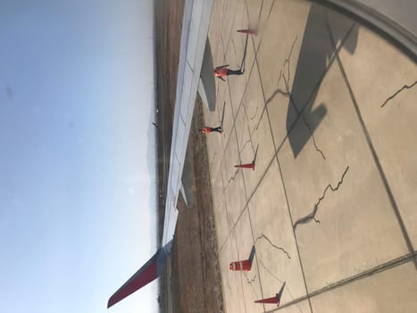 Ground crew member directing an airplane on the airport apron, seen through a cabin window