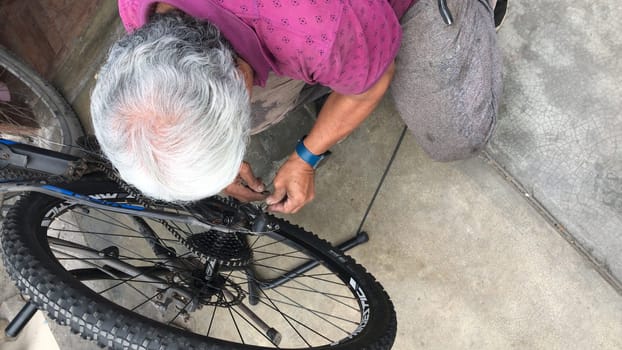 Elderly lady fixing a bike tire at home, showcasing active lifestyle