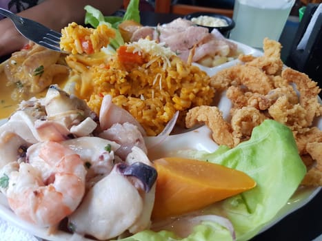 Colorful dish of mixed seafood, spicy rice, and fresh salad on a plate