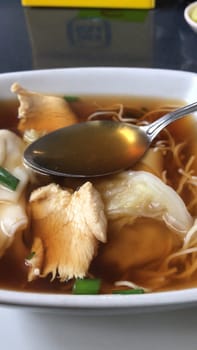 Delicious bowl of asian chicken soup with noodles, greens, and broth