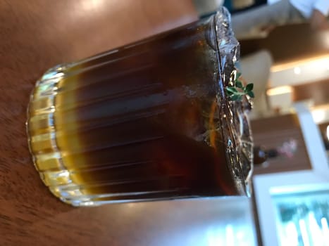 Close-up of a chilled iced tea adorned with fresh thyme, on a wooden surface