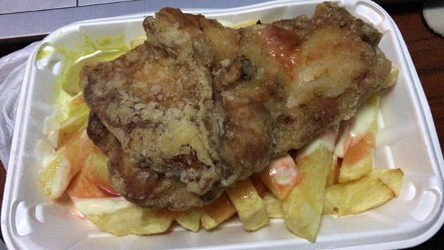 Crispy fried chicken paired with golden fries and salad in a white styrofoam container