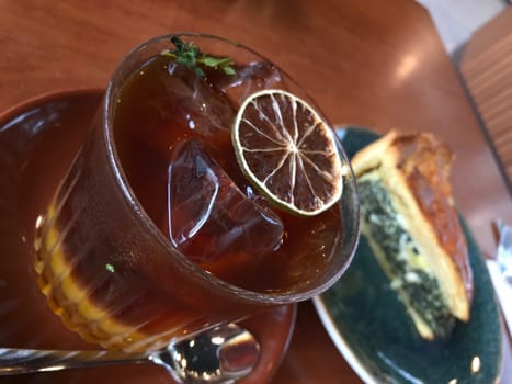 Cold glass of iced tea with lemon beside a savory slice of quiche