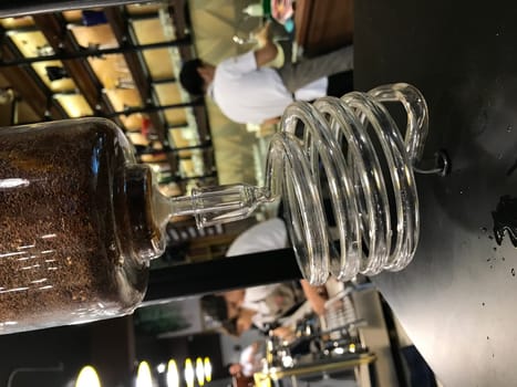 Close-up of an elegant glass cold brew coffee dripper with a cafe background