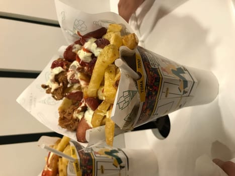 Delicious loaded hot dogs with a variety of sauces and toppings in paper cones