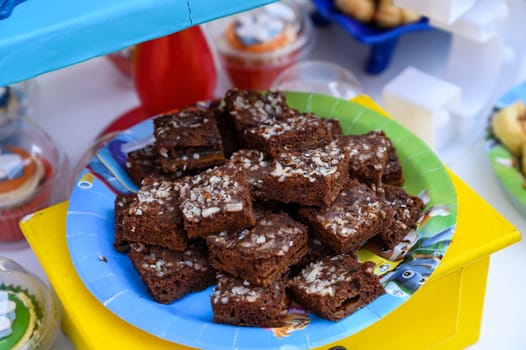 Delightful homemade brownies sprinkled with coconut flakes on a vibrant plate at a party setting
