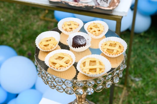 Selection of mini apple and chocolate pies displayed on a stylish glass stand at an outdoor event