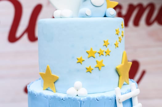 Close-up of a blue fondant cake decorated with yellow stars and white accents for celebrations