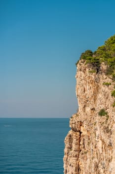 Sheer cliff in sunlight, blue water and clear sky of Dugi Otok island, Telascica National Park, Croatia