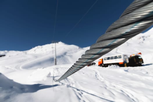 Steel cable of a cable car close-up. Rope texture. The path of the cable cabin against the backdrop of snow-capped mountains.