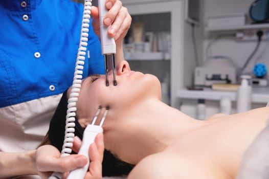 Close-up of a woman receiving an electric neck massage with equipment in a beauty salon. Used for therapy with a multifunctional electro massage device.