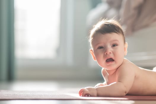 Cute little boy crying lying on his stomach on the floor