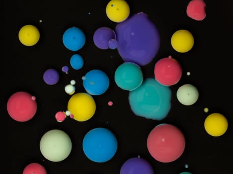 A close-up shot of vibrant paint droplets suspended in a black liquid, creating a mesmerizing abstract pattern. Creating a mesmerizing effect reminiscent of a galaxy.
