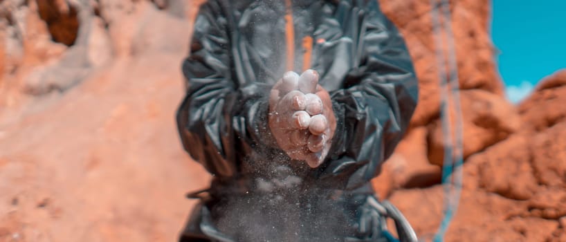 The girl is engaged in rock climbing, uses white powder of magnesia, claps her hands close-up, the woman leads an active lifestyle, climbs the mountains outdoor.