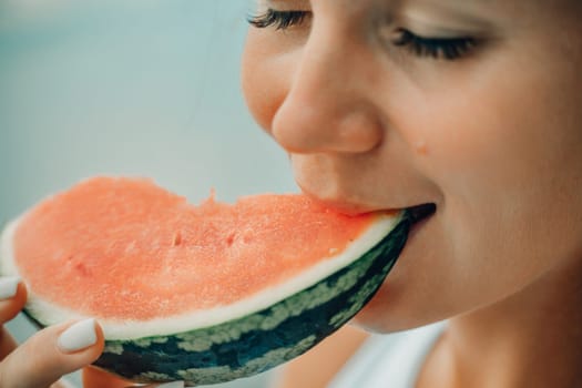 A woman is eating a watermelon slice. The watermelon is cut in half and is being eaten by the woman