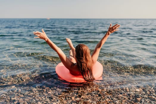 A woman is in the ocean on a red inflatable raft. She is smiling and she is enjoying herself