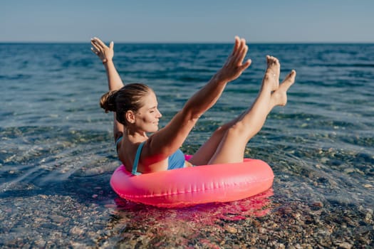 A woman is floating in a pink inflatable ring in the ocean. She is smiling and she is enjoying herself
