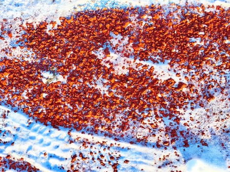 Red pebbles or rubberized textured material and white snow on it. Background, texture, frame, copy space. Contrast of red pebbles and white snow creating textured backdrop