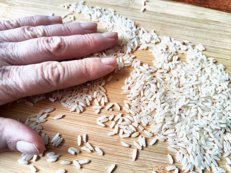 Rice in the hand on a palm of woman. Grits for cooking. Texture, background, copy space and place for text