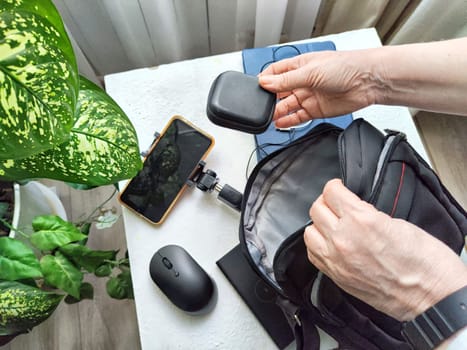 A set of useful blogger devices and hand of female blogger. A neatly organized desk featuring a smartphone, earphones, and various tech gadgets