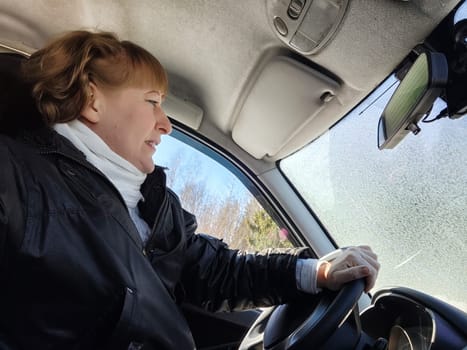 Middle aged woman in a car taking a selfie while enjoying a drive. Female mature driver posing inside car. Funny happy tourist girl in alone travel