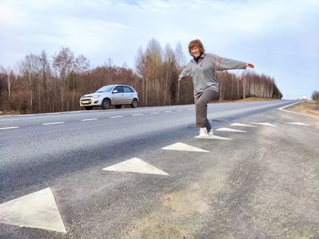 Woman Balancing on Road Marking During Roadside Travel Break. Woman enjoying playful balance walk next to parked car on roadside
