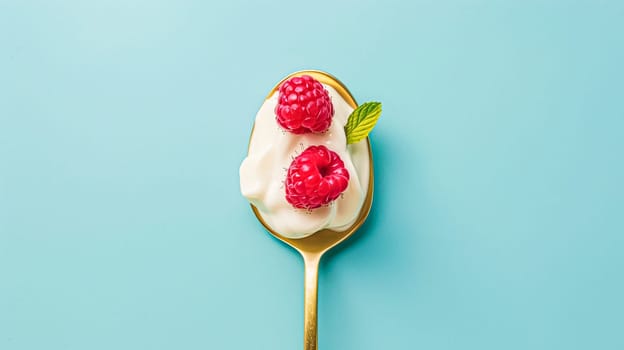 Golden spoon filled with creamy yoghurt and topped with fresh raspberries