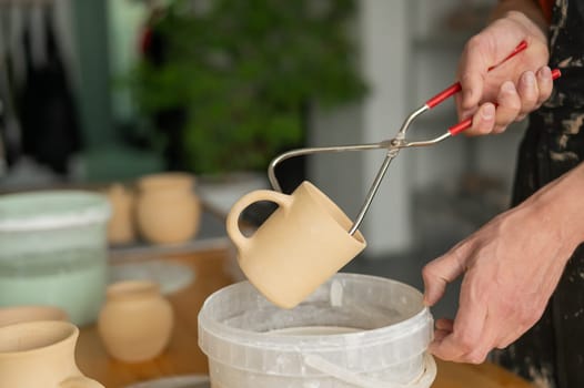 Close-up of a potter's hands glazing a ceramic mug