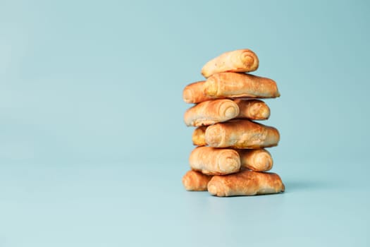 Bagels stacked on a blue background. Sweet pastries for tea, copy space.