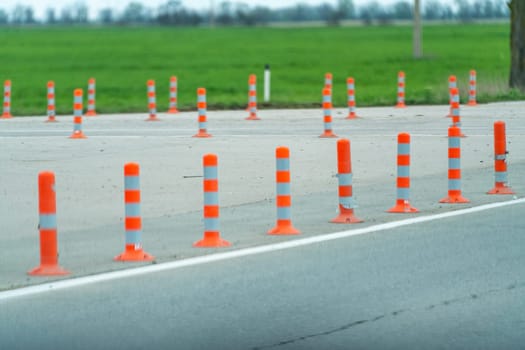 A row of orange and white traffic cones are lined up on a road. The cones are spaced out and are not in use