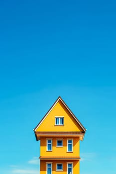 A yellow house with a blue roof and blue trim. The house is tall and has a chimney