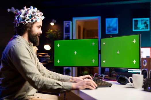 Neuroscientist using EEG headset and isolated screen multi monitor setup to upload mind into computer. Engineer using chroma key PC, experimenting with transferring consciousness into cyberspace