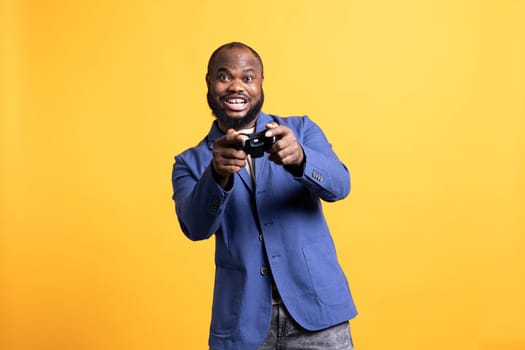 Cheerful player happy after winning gaming console game, isolated over studio background. Joyful man satisfied after being victorious in videogame, defeating all enemies using gamepad