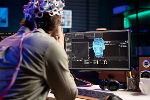 IT professional using EEG headset to communicate with artificial intelligence on computer in binary code. Software developer sending brainwave signals to AI entity on PC using high tech device