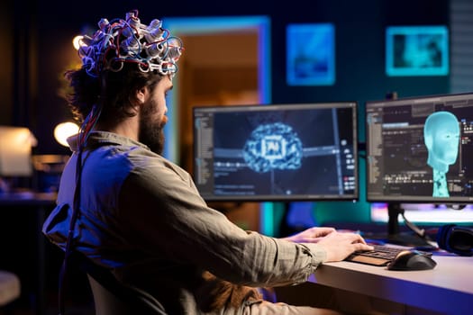 Developer with EEG headset on programming brain transfer into computer virtual world, becoming one with AI. Transhumanist using neuroscientific tech to transcend physical limitations