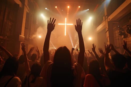 A large crowd of christian people are gathered in a church, with their hands raised in the air and a large cross in the center of the room. The atmosphere is one of worship and unity