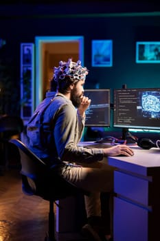 Man puts EEG headset on to transfer mind into computer virtual world, becoming one with AI superintelligence. Engineer using futuristic neuroscientific technology to transfer consciousness