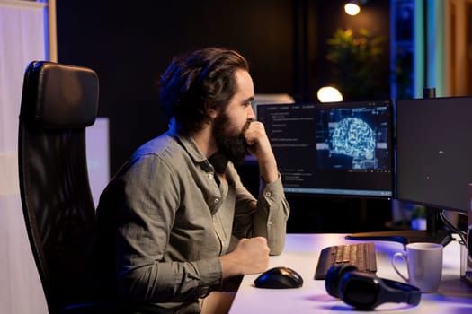 Programmer updating artificial intelligence deep learning algorithm, writing binary code scripts. IT specialist in apartment office uses programming to upgrade AI, waiting for software to load