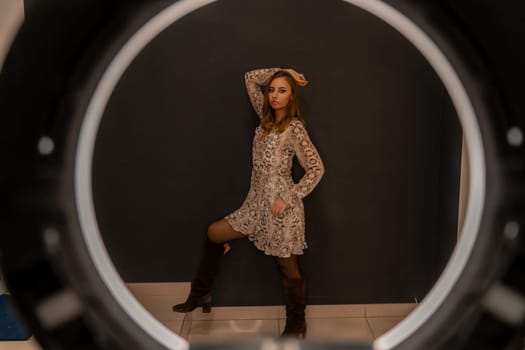 A woman in a leopard print dress is posing for a photo in front of a blue background