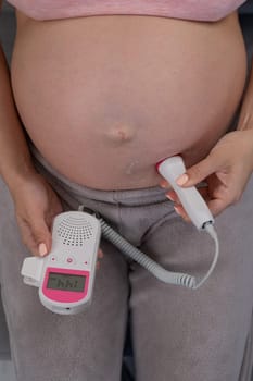 Close-up of a pregnant woman's belly using a home doppler. Normal baby heartbeat