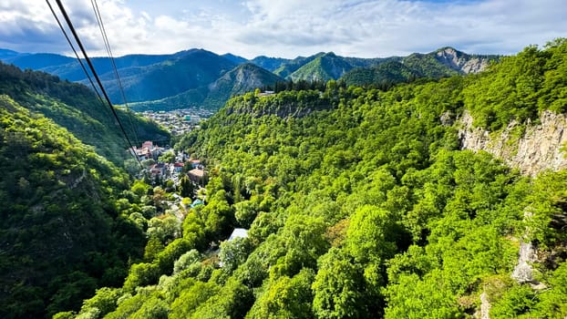 Georgia. Borjomi Historical Park. View from the cable car funicular. May 19, 2024. Scenic aerial view of lush green valley with village nestled among the mountains under sky with clouds. High quality