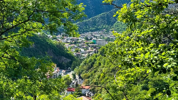 Grztya, Tbilisi. Borjomi Historical Park. May 19, 2024. Scenic aerial view of lush green valley with village nestled among the mountains under blue sky with clouds. Travel photography. High quality