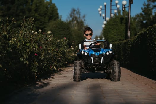 boy rides in a toy mini car in the park in summer