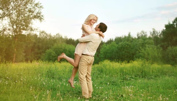 Portrait of beautiful happy smiling young couple in love together hugging in green summer park