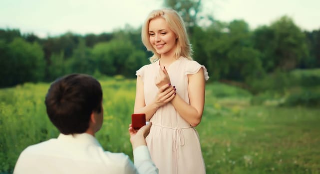 Wedding concept, happy lovely young couple, man proposing a ring to his beloved woman outdoors in summer park