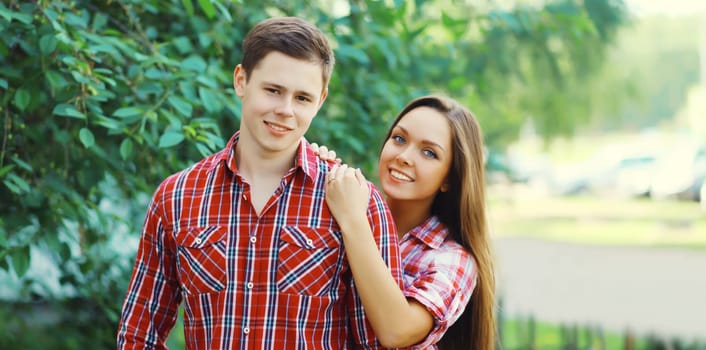 Portrait of happy smiling caucasian young couple together outdoors standing in summer park