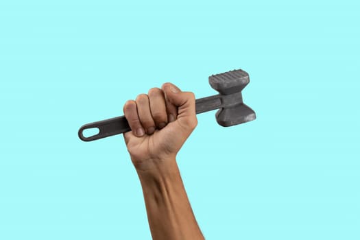 Black male hand holding a kitchen hammer isolated on cyan background. High quality photo