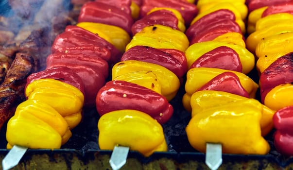 A close-up shot featuring a colorful assortment of bell peppers skewered and ready for grilling. The vibrant red and yellow peppers offer a burst of flavor, ideal for a summer barbecue in the garden.