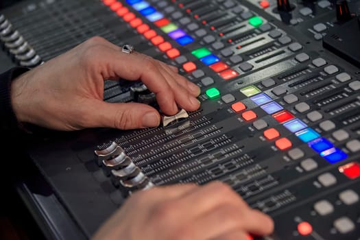Audio engineer on audio mixer in studio adjusting volume levels. Broadcast, Music production, Sound engineer, Mixing console, Fader, Knob, Button. Isolated on black background